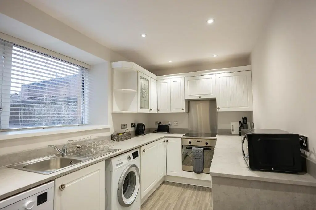 a kitchen with white cabinets and a sink and a tv at New Inn Hotel in Ellon