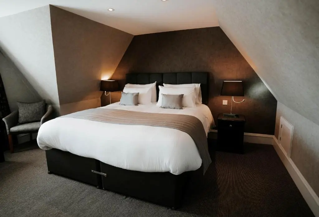 a bedroom with a large bed with white sheets and pillows at New Inn Hotel in Ellon