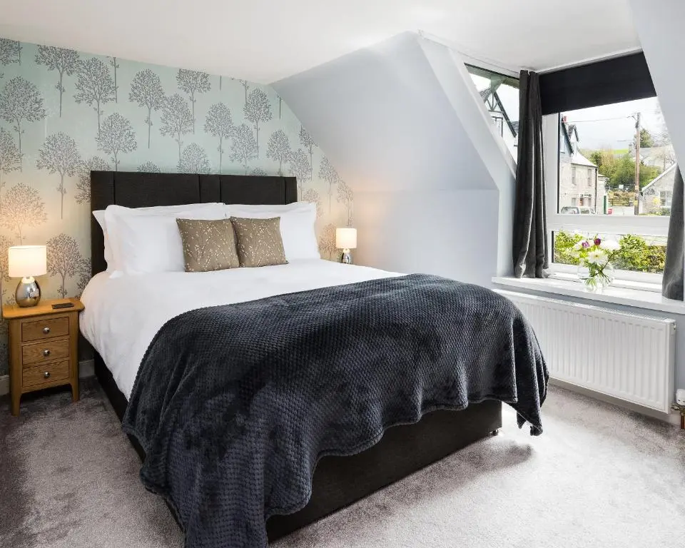 a bedroom with a large bed with a black blanket at Smithy Cottage in Kirkmichael