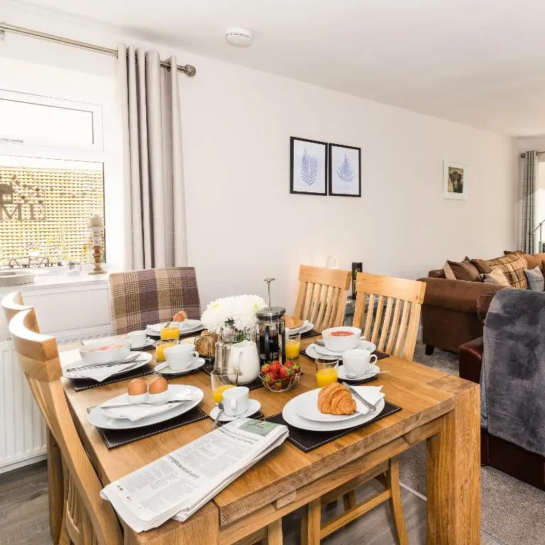 a dining room with a wooden table with food on it at Smithy Cottage in Kirkmichael
