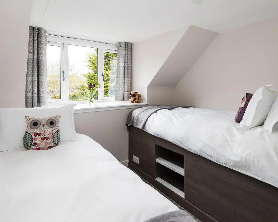 a bedroom with two beds and a window at Smithy Cottage in Kirkmichael