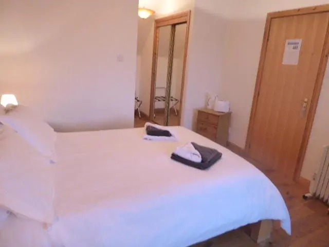 a bedroom with a white bed with two towels on it at Dacama House Accommodation in Ullapool