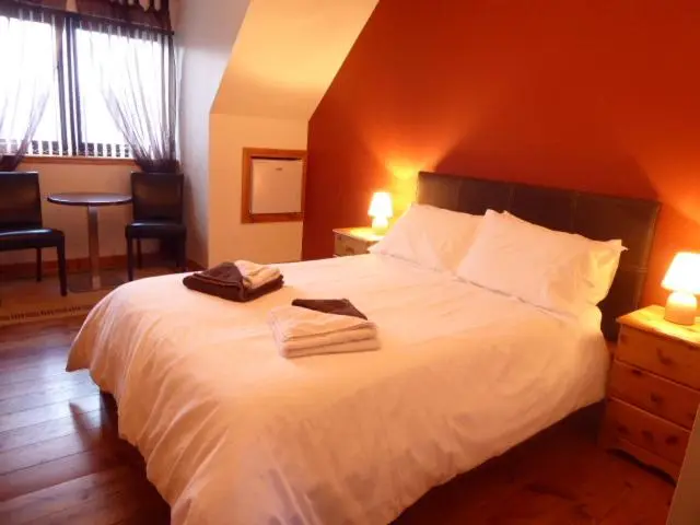 a bedroom with a white bed with two towels on it at Dacama House Accommodation in Ullapool