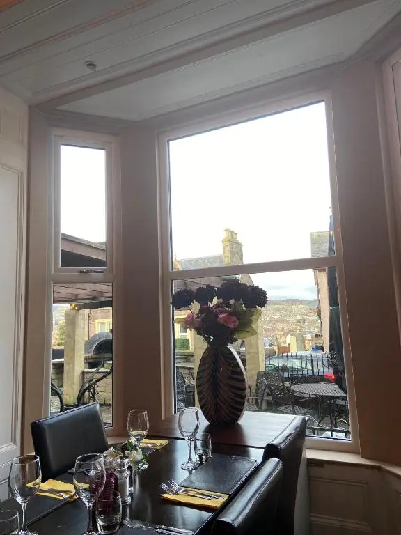 a table with a vase of flowers and a window at Redcliffe Hotel in Inverness