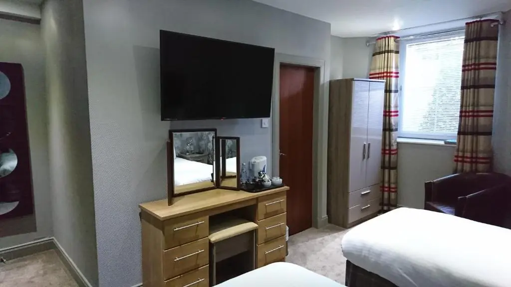 a bedroom with a mirror and a tv on the wall at Redcliffe Hotel in Inverness