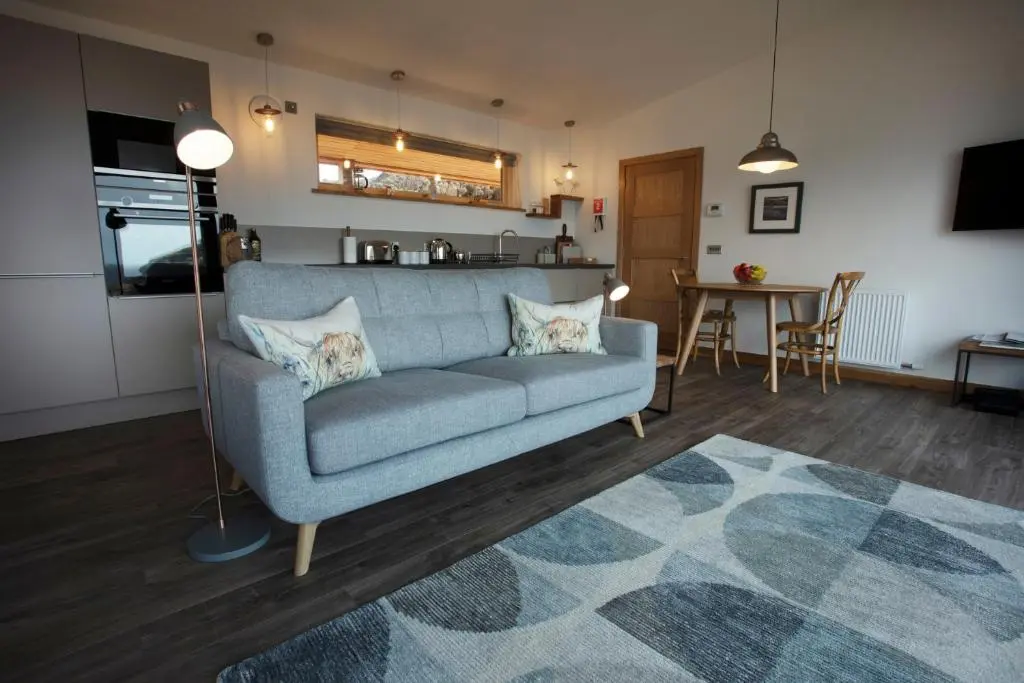 a living room with a blue couch and a kitchen at Tigh na Mara in Ullapool