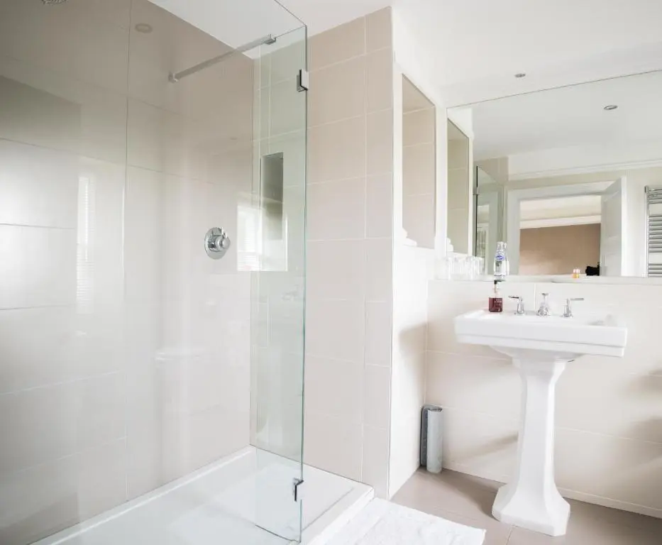 a white bathroom with a shower and a sink at The Redgarth in Oldmeldrum