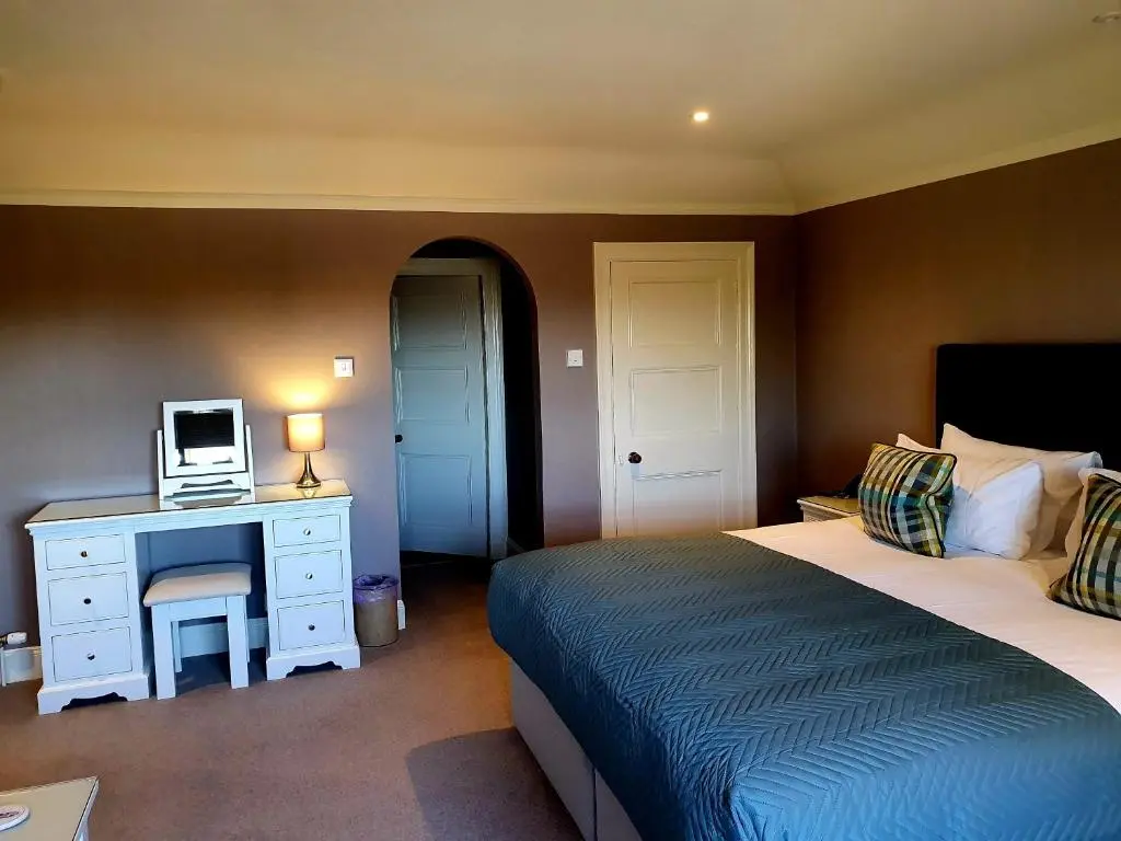 a bedroom with a bed and a desk with a computer on it at The Redgarth in Oldmeldrum