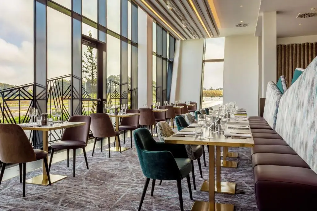 a restaurant with tables and chairs and large windows at Hilton Aberdeen TECA in Aberdeen