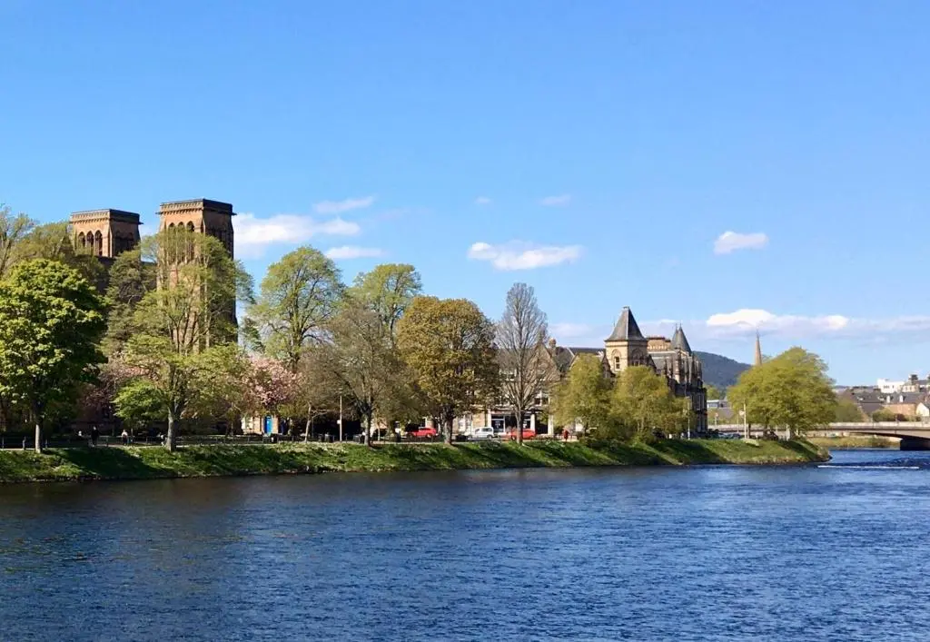a view of a river with a building and a bridge at Wellingtonia Court Apartment in Inverness