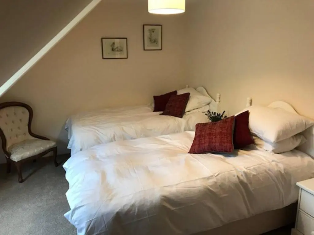 a bedroom with two beds and a chair at Traditional Family Home in Royal Deeside in Aboyne