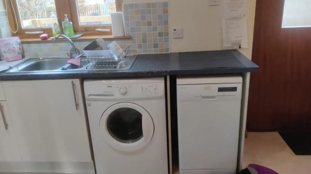 a kitchen with a washing machine and a sink at Sunbury Aviemore in Aviemore