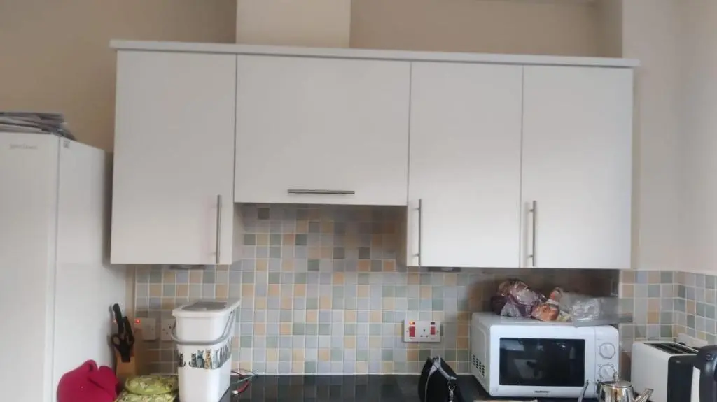 a kitchen with white cabinets and a microwave at Sunbury Aviemore in Aviemore
