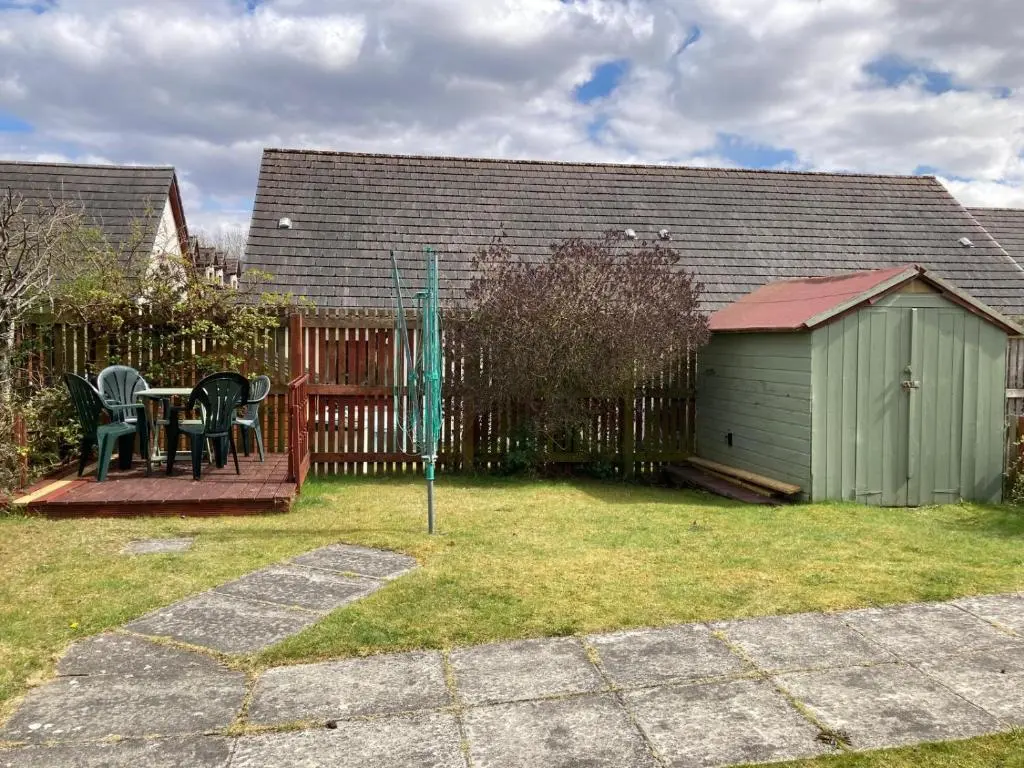 a backyard with a table and chairs and a fence at Sunbury Aviemore in Aviemore