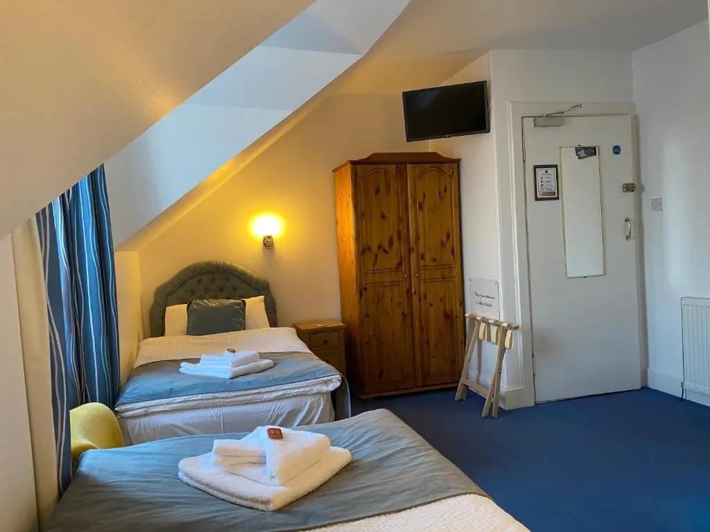a hotel room with two beds and a tv at Garden Park Guest House in Grantown on Spey