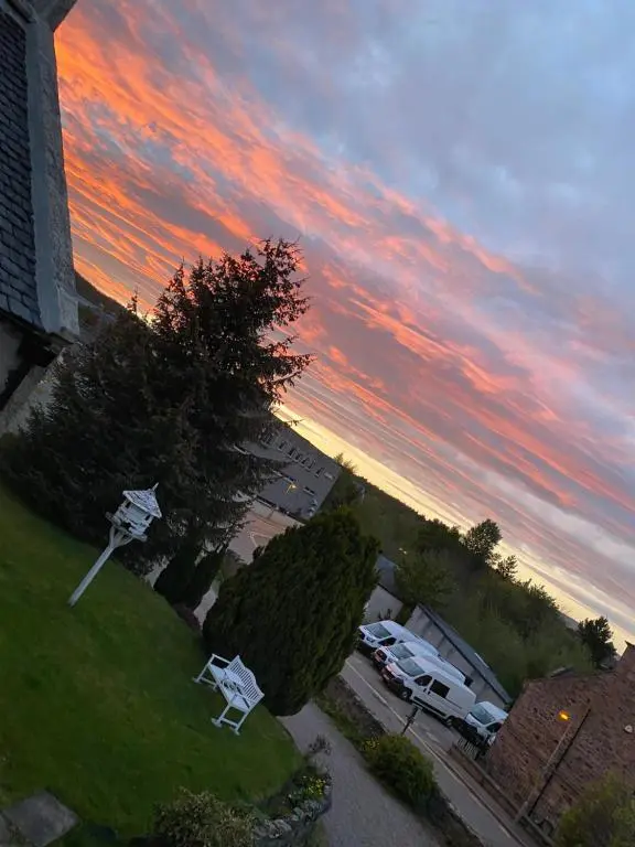 a sunset with cars parked in a parking lot at Garden Park Guest House in Grantown on Spey