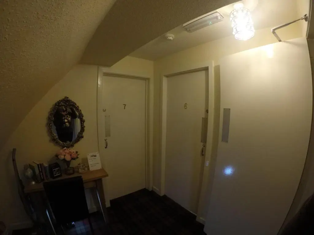 a hallway with a door and a table with a mirror at No 29 Bed and Breakfast in Inverness
