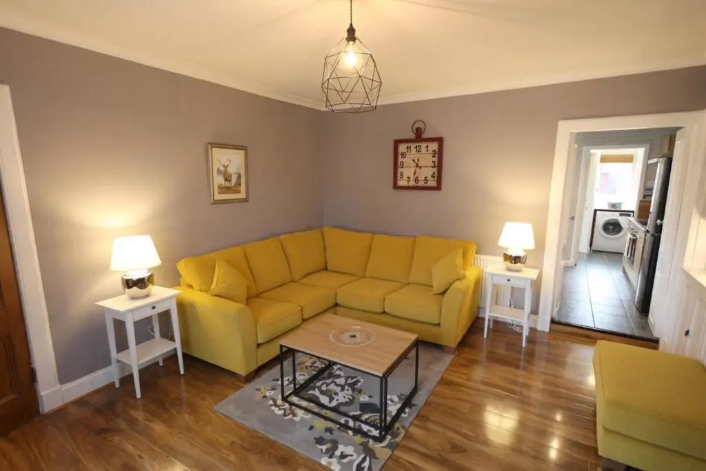 a living room with a yellow couch and two tables at Arrandale in Inverness