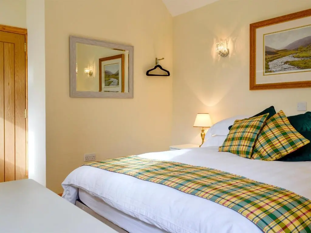 a bedroom with two beds and a mirror at The Old Inverchroskie Kennels in Enochdhu