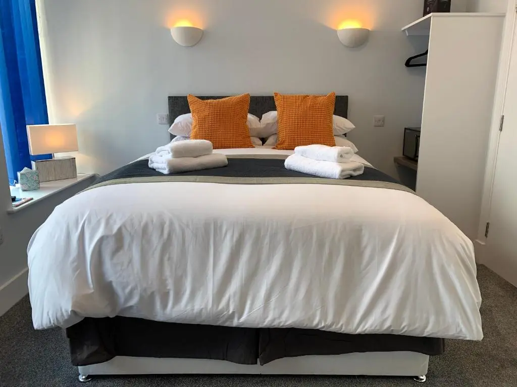 a bedroom with a large bed with orange and white pillows at Muir Bank in Muir of Ord