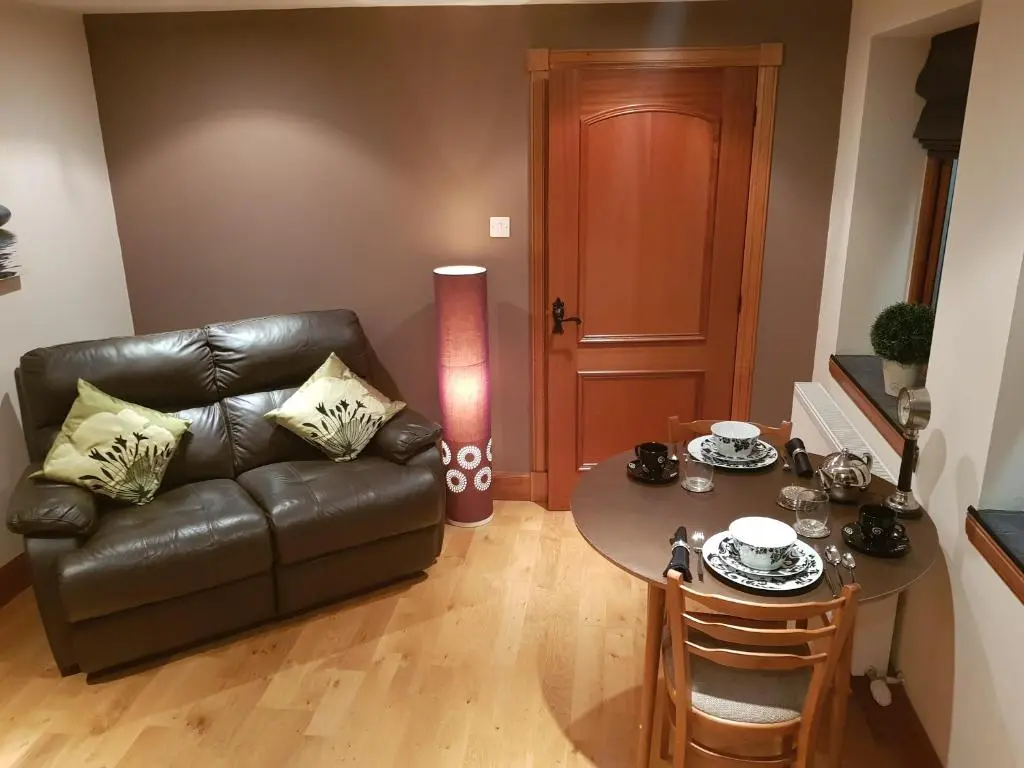 a living room with a leather couch and a table at The Smiddy Suite in Ellon
