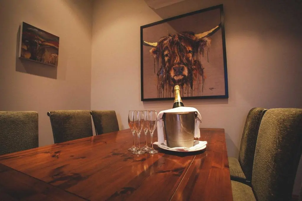 a table with a bottle of wine and glasses on it at Meldrum House Hotel Golf And Country Estate in Oldmeldrum
