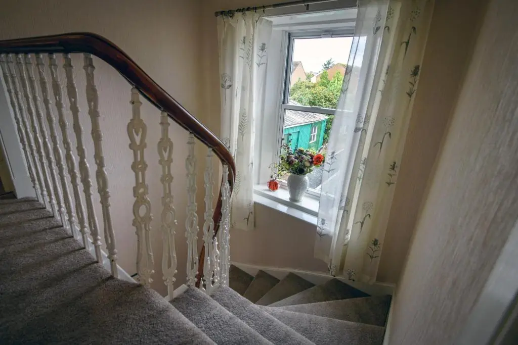 a staircase leading to a window with a plant on the window sill at Charming Townhouse on North Coast 500 Route, Wick in Wick
