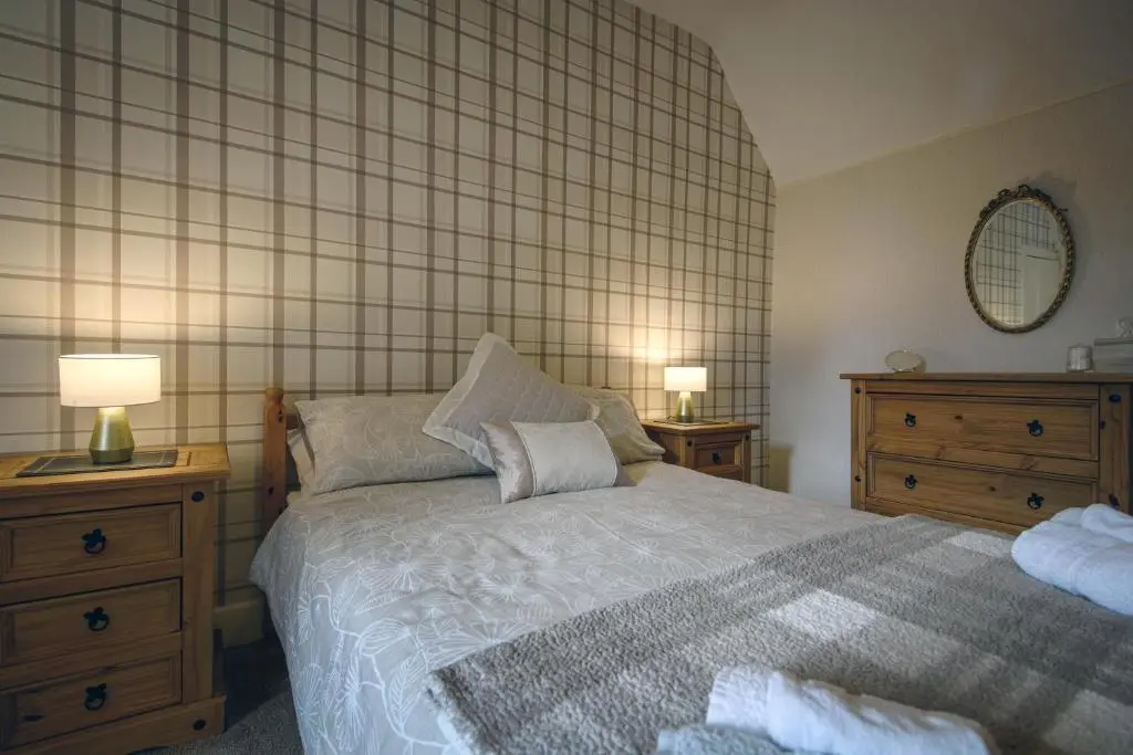 a bedroom with a bed and two dressers and a mirror at Charming Townhouse on North Coast 500 Route, Wick in Wick