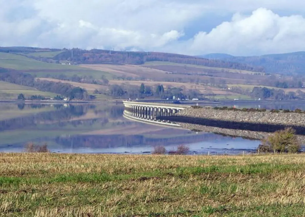 a bridge over a body of water in a field at Kirkside Holiday Home in Alness