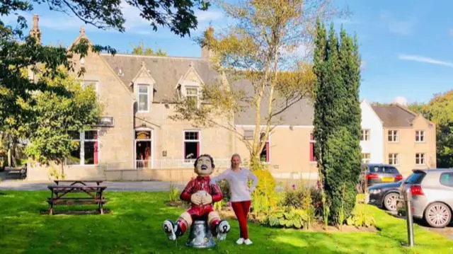 a man and woman standing in front of a house at Pinehurst Lodge Hotel -Dyce, Aberdeen in Dyce