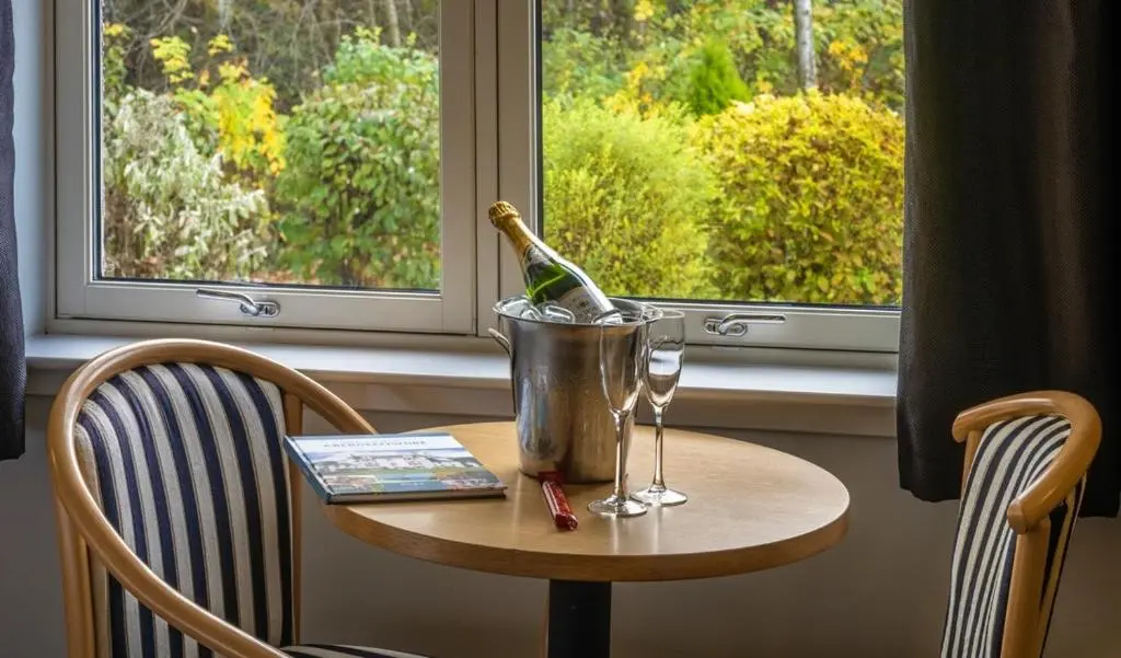 a table with a bottle of wine and a bucket at Pinehurst Lodge Hotel -Dyce, Aberdeen in Dyce
