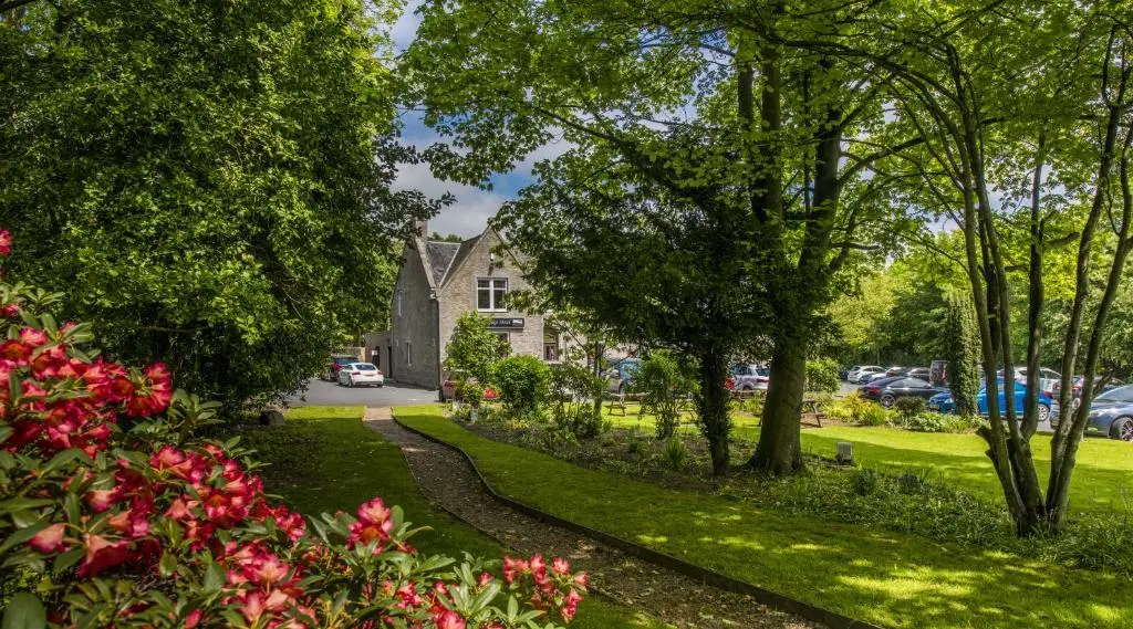 a path through a park with trees and flowers at Pinehurst Lodge Hotel -Dyce, Aberdeen in Dyce