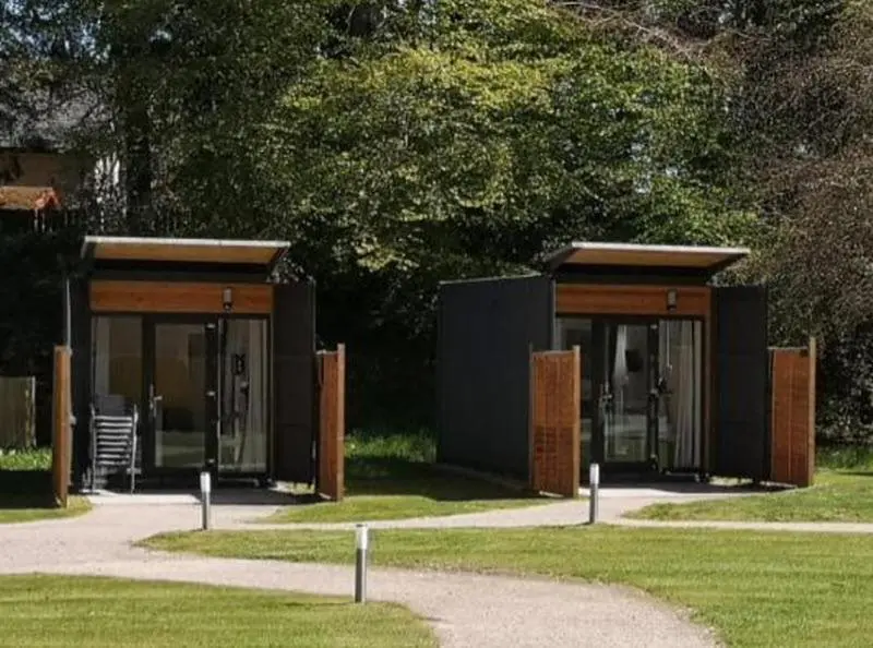 a small building with glass doors in a park at A UNIQUE Experience in a Converted Shipping Containers, Glamness is Adults Only in Inverness