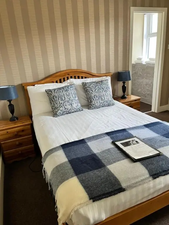 a bedroom with a bed with a blanket and two lamps at Ord Arms Hotel in Muir of Ord
