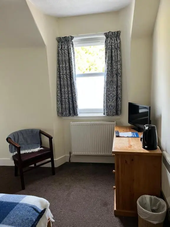 a bedroom with a desk and a window with a television at Ord Arms Hotel in Muir of Ord