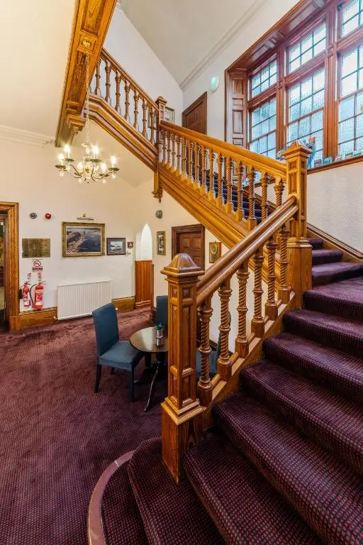 a spiral staircase in a room with a table and chairs at Inverness Lochardil House, by Highland Coast Hotels in Inverness