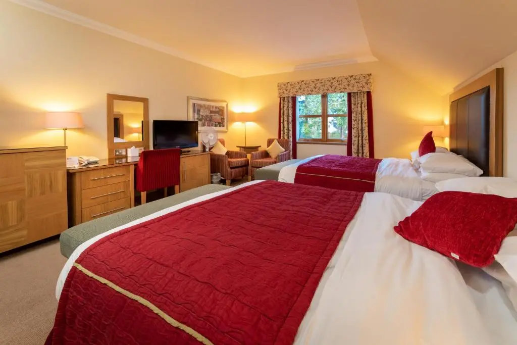 a hotel room with two beds and a television at Inverness Lochardil House, by Highland Coast Hotels in Inverness