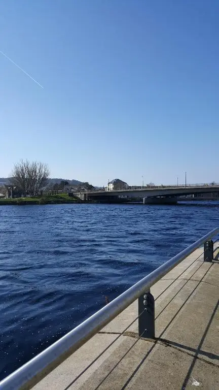 a view of a river with a metal railing at exploreNESS Apartment in Inverness