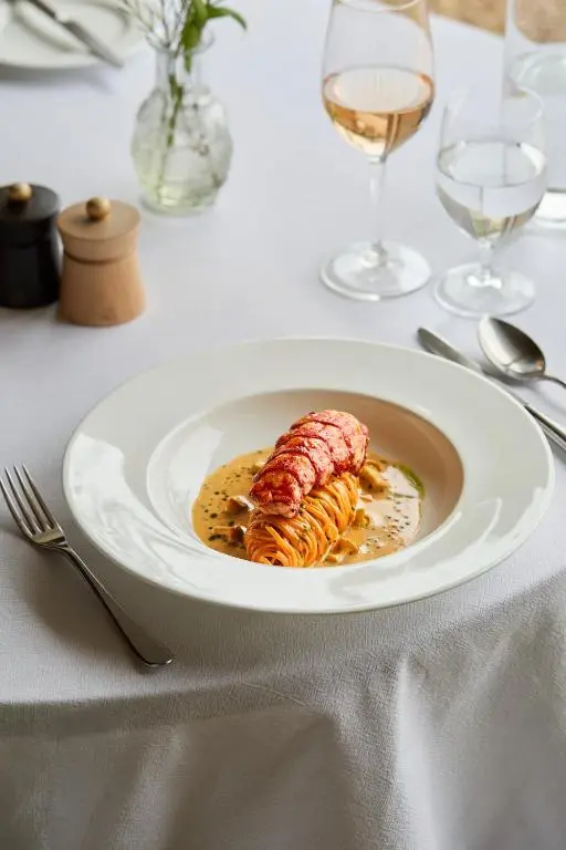 a plate of food on a table with wine glasses at Newhall Mains in Resolis