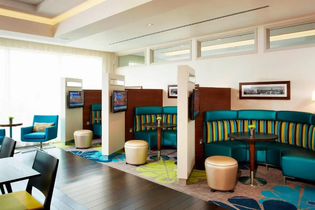 a waiting room with blue chairs and tables at Courtyard by Marriott Aberdeen Airport in Dyce