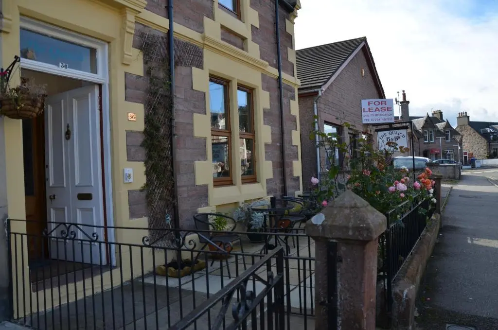 a building with a fence and flowers on a street at The Quaich B&B in Inverness