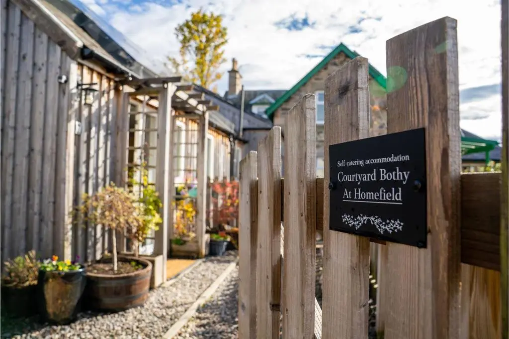 a sign on a fence in front of a garden facility at Courtyard Bothy in Grantown on Spey
