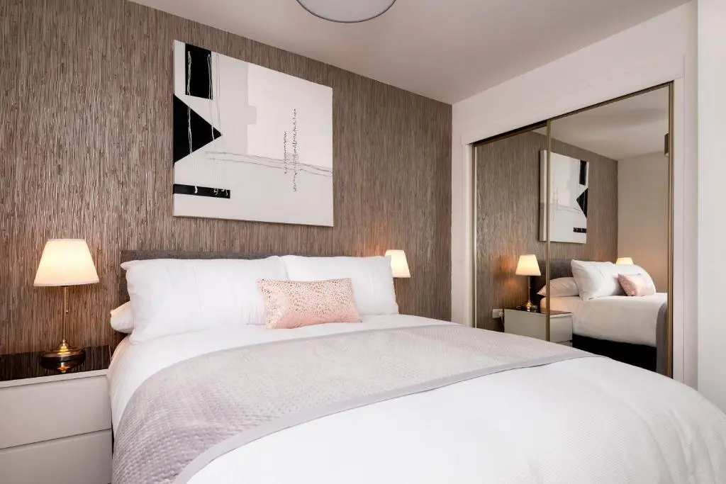 a bedroom with a white bed and a mirror at No. 6 Apartment in Inverness