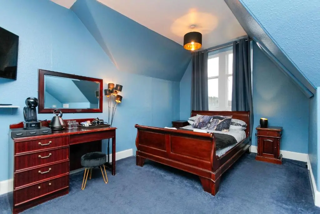 a bedroom with a bed and a desk and a mirror at Carlton Hotel in Forres