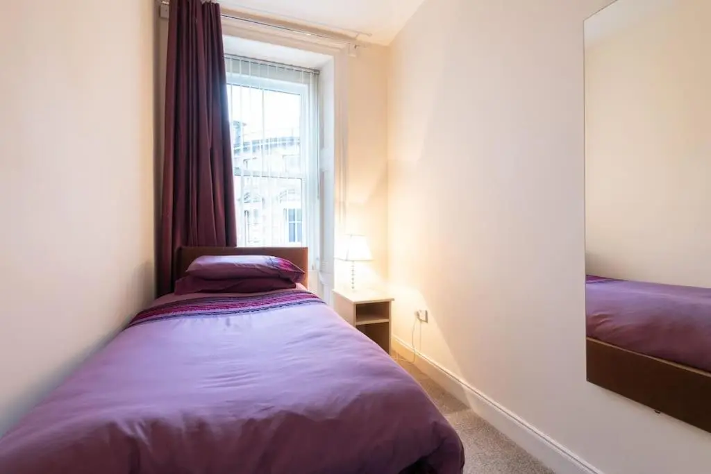 a small bedroom with a bed and a window at CASTLEBANK HOUSE FLATS, DINGWALL in Dingwall