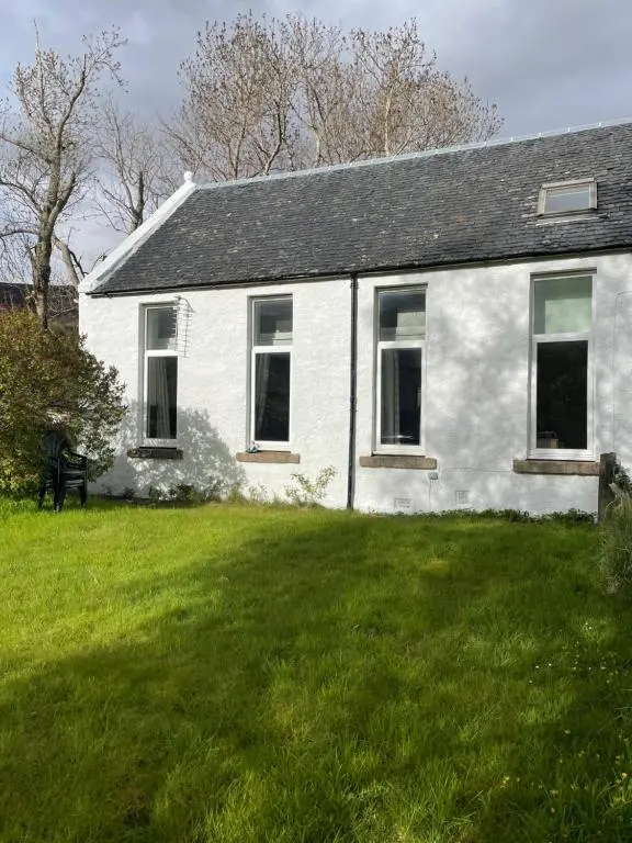 a white house with a green lawn in front of it at Inverlael Farm Cottages in Inverlael