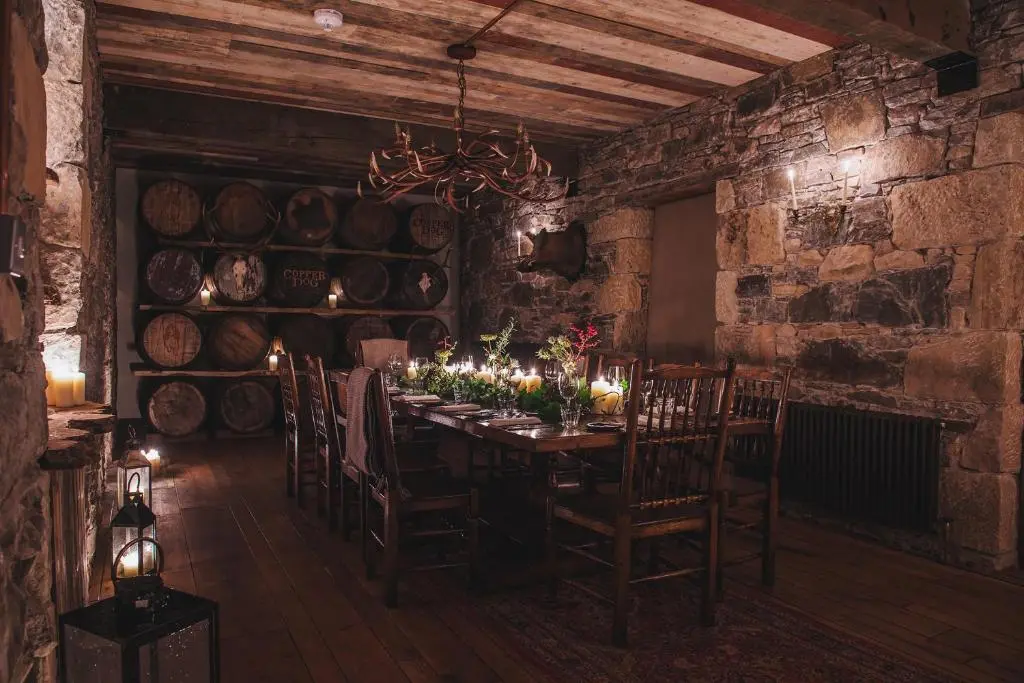 a dining room with a table and some wine barrels at Dandaleith Cottage No.1 in Craigellachie