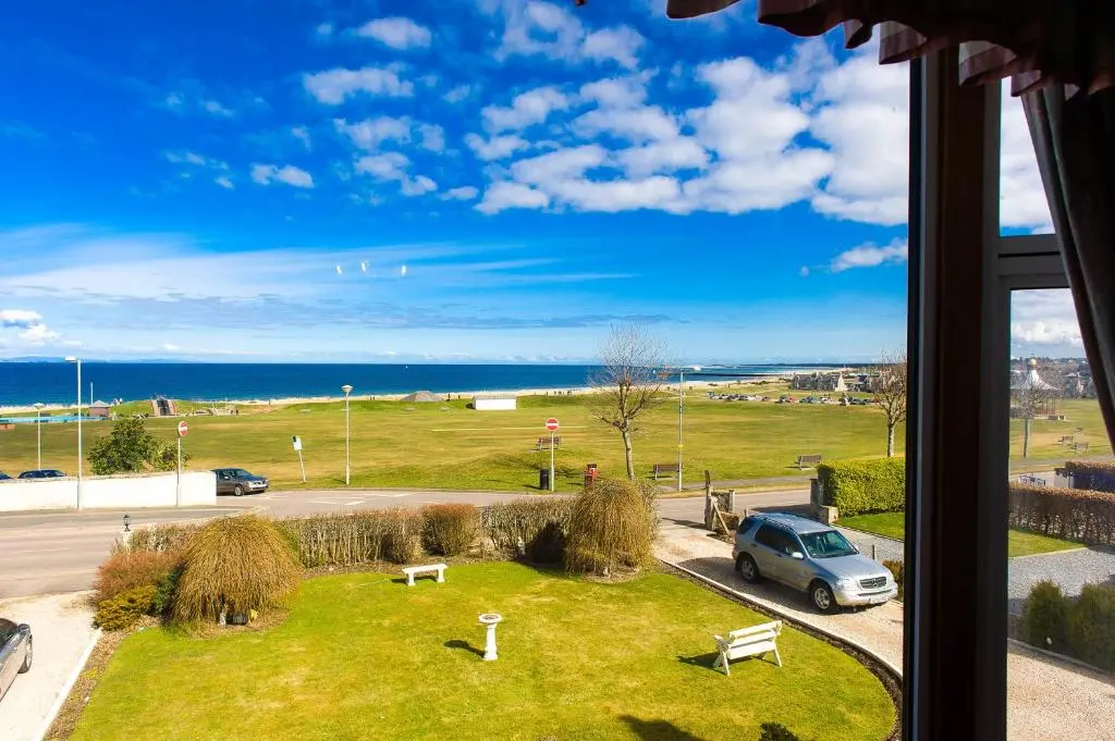 a window with a view of a car parked in a field at "Stunning Sea-Views" at Wetherby Nairn in Nairn