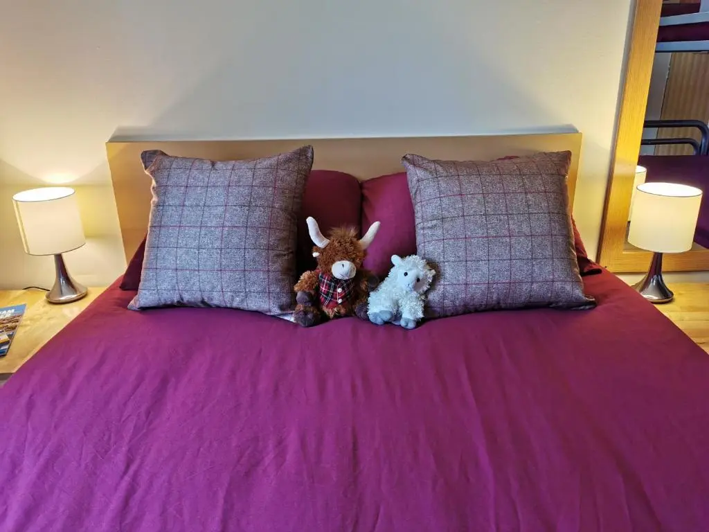 two stuffed animals sitting on top of a bed at Morag's Lodge in Fort Augustus