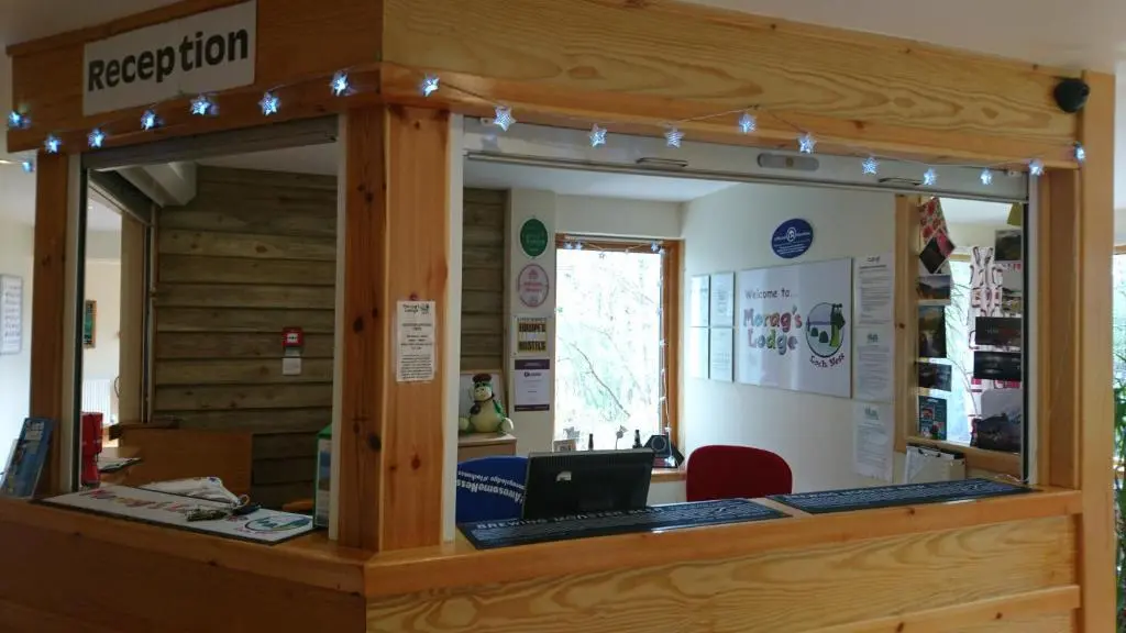 a reception desk with a laptop on top of it at Morag's Lodge in Fort Augustus
